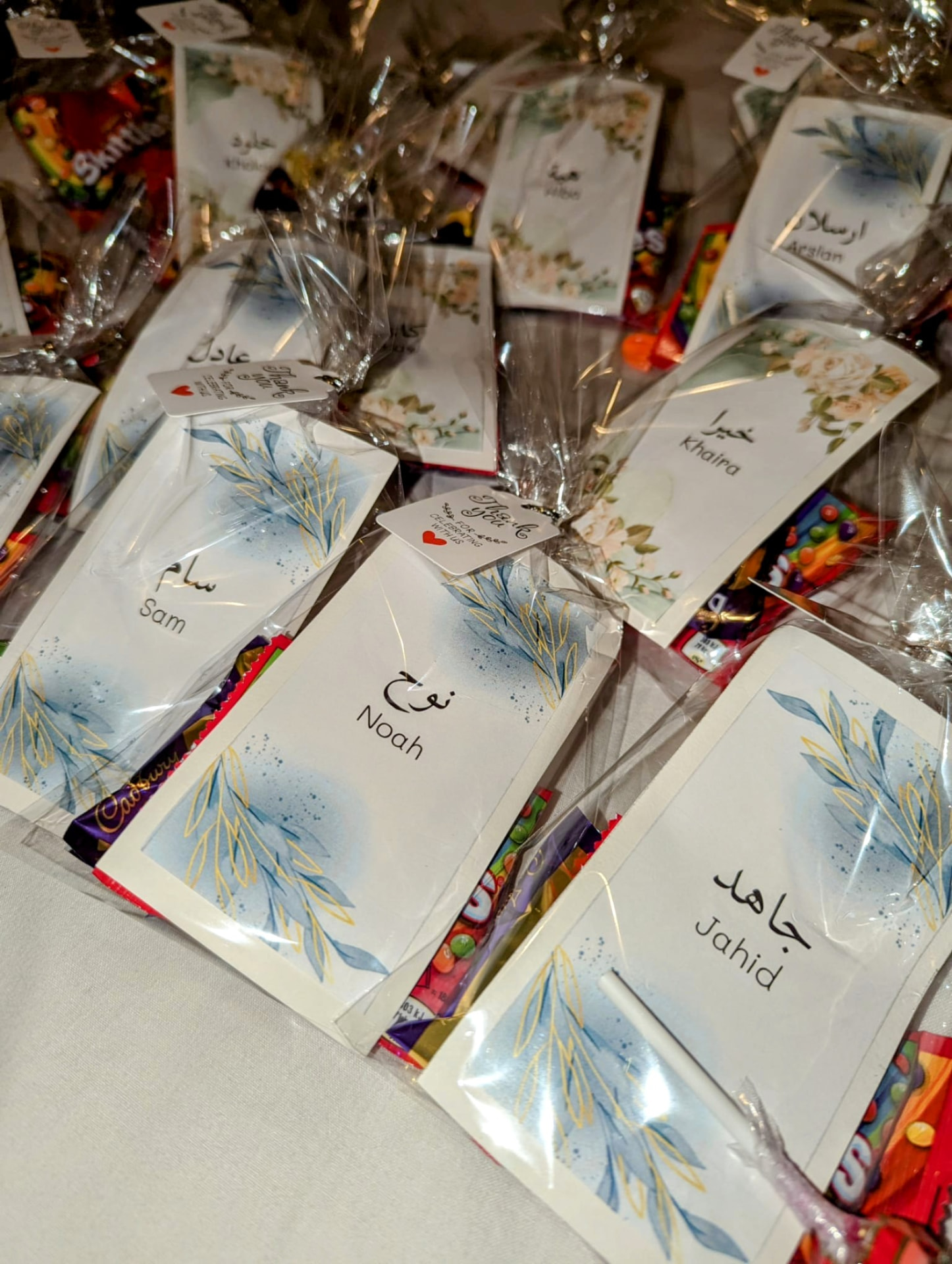 Cellophane sweet bags each with a card carrying a name in Arabic and English