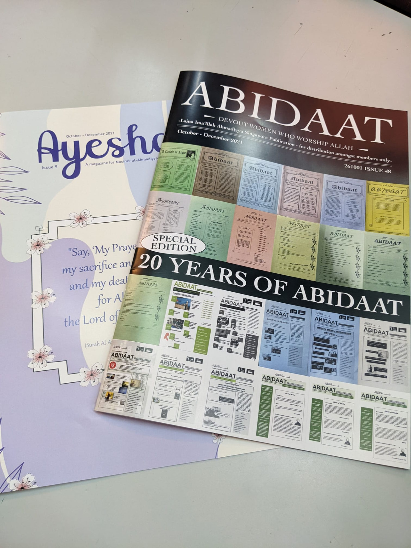 Abidaat twentieth-anniversary special edition, its cover a grid of past front pages, beside the Ayesha magazine